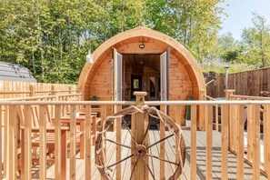 Eine Holzhütte mit offener Tür, einem Rollstuhl und einer Terrasse mit Geländer.