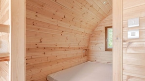 A small wooden cabin with a single bed, a window, and a door. - Livi Family Pod - hot tub (Thirsk)