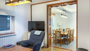 Un salon moderne avec une table à manger en bois, un téléviseur et un fauteuil confortable.