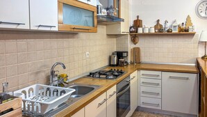 Une cuisine moderne équipée d’une cuisinière à gaz, d’un évier et de meubles de rangement en bois.
