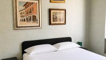 Une chambre à coucher avec un lit, une table de chevet et deux tableaux encadrés accrochés au mur.