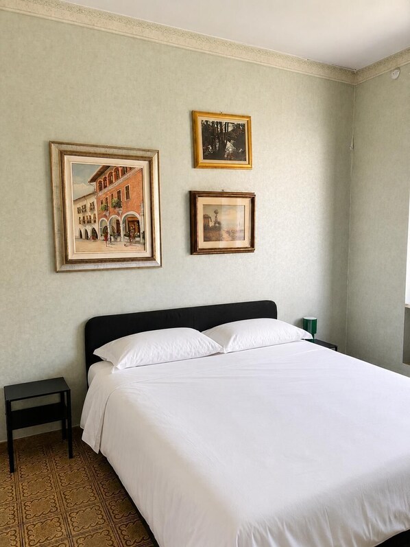 Una camera da letto con un letto, un comodino e due quadri appesi al muro.