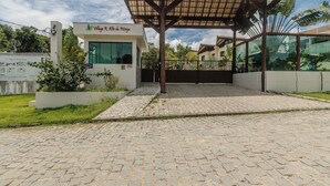 A building with a covered entrance, a sign reading "Vila do Pilinho," and a paved driveway. - Yellow House - Pitinga Beach - Arraial d'Ajuda (Arraial d'Ajuda)