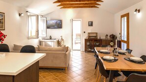 A dining area with a wooden table set for four, a sofa, and a television in the background. - Beautiful home in Supetar with WiFi (Supetar)