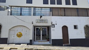 Et hotel med et skilt, der siger "HOTEL" over indgangen, en stor buet dør og et skilt med "COCHERA SIDERAL".