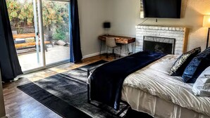 Quarto com cama, escrivaninha, lareira e televisão.