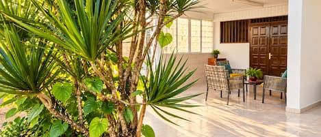 Un espace patio aménagé avec des sièges, un pot de fleurs et une porte visible au fond.
