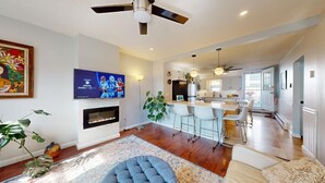 A modern living room with a fireplace, a television, and a dining area with bar stools. - Stylish East Boston Gem, Near Downtown, T and Airport (Boston)
