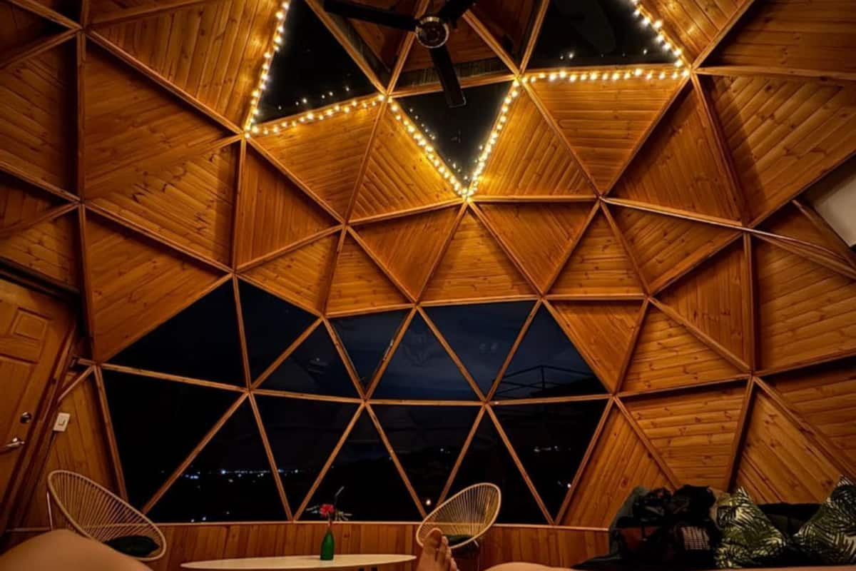 A room with a geometric wooden ceiling design and string lights.