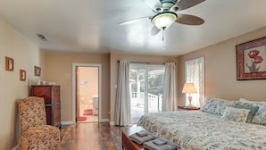 Ein Schlafzimmer mit einem Bett, einem Sessel, einer Bank, einem Deckenventilator und einer Tür, die auf einen Balkon führt.
