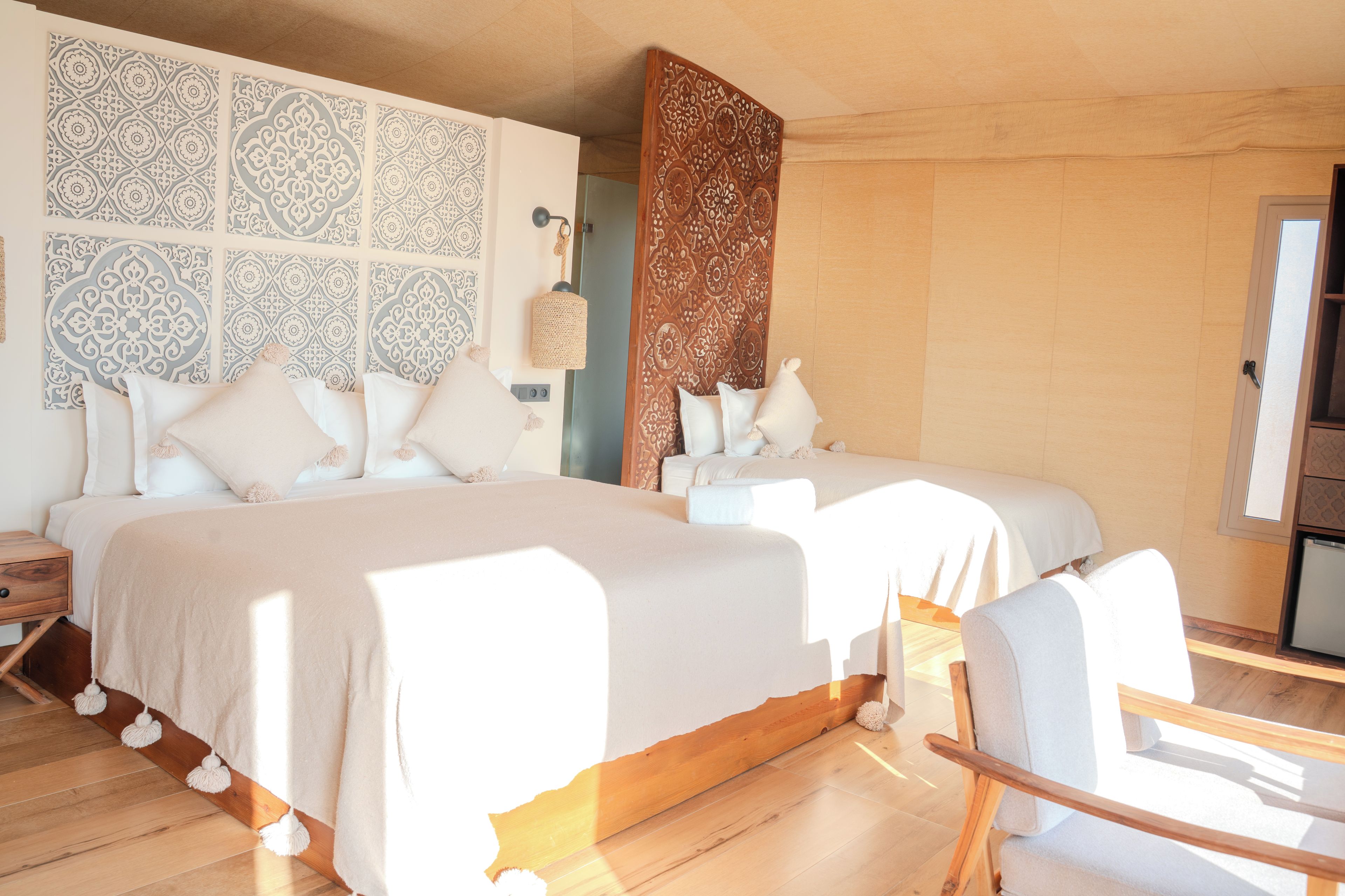 A bedroom with two beds, a wooden floor, and a wall with decorative panels.