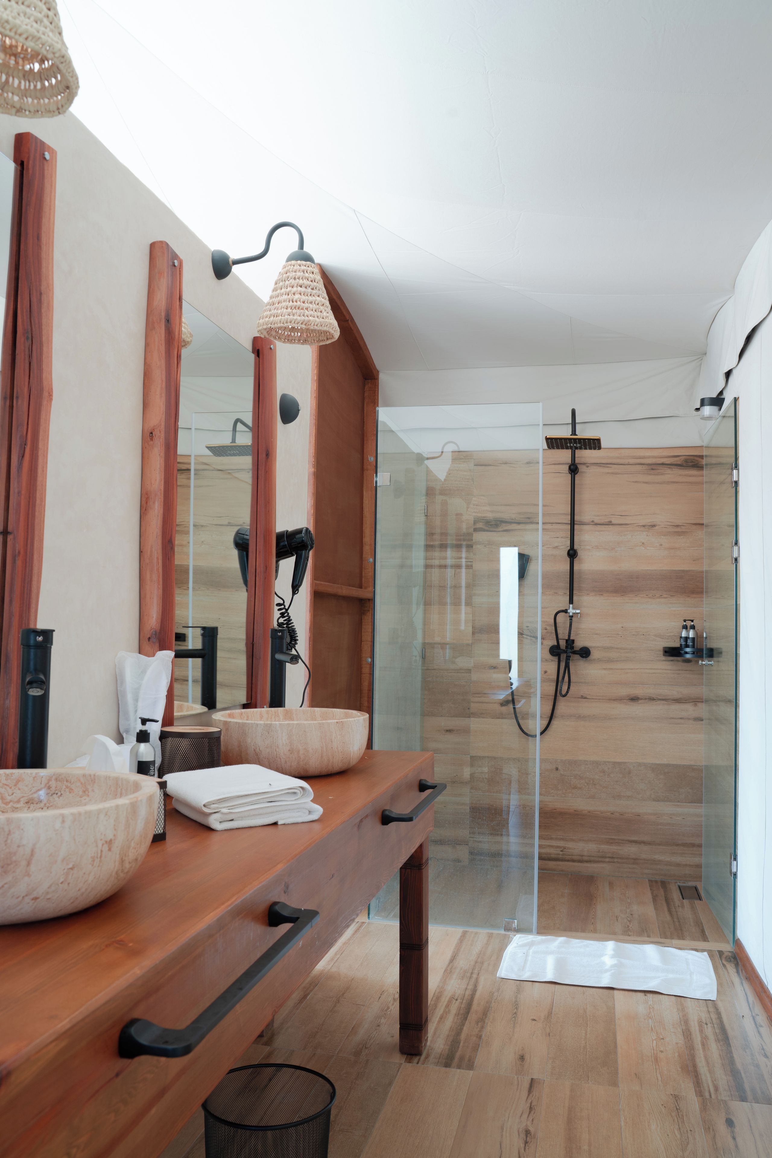 Un baño moderno con tocador de madera, un espejo grande y cabina de ducha de vidrio.