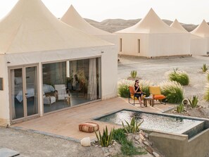 Een woestijnhotel met diverse tenten, een zwembad en buitenmeubilair.