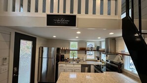 A modern kitchen with a stainless steel refrigerator, a double sink, and a granite countertop. - 2 Homes Mentone Getaway | Riverfront & Near Parks (Mentone)
