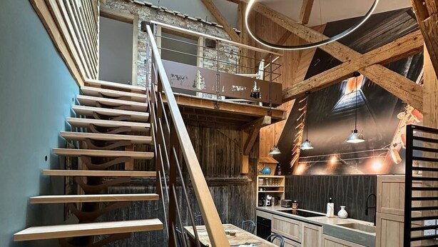 A modern interior with a wooden staircase, a dining area, and a kitchen with a skylight. - Authentic stay in Haut-Doubs (Morteau)