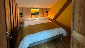 A cozy bedroom with a wooden slat wall, a bed with white bedding, a nightstand, and a wall-mounted lamp. - Authentic stay in Haut-Doubs (Morteau)