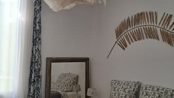 A bedroom with a bed, a mirror, a wall-mounted feather decoration, and a ceiling fan.