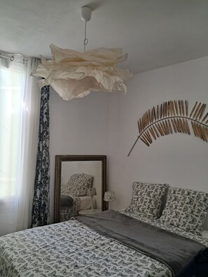 Ein Schlafzimmer mit einem Bett, einem Spiegel, einer Wanddekoration aus Federn und einem Deckenventilator.