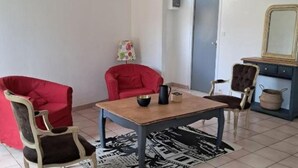 Une pièce comprenant une table, deux chaises rouges, un tapis noir et blanc et un miroir accroché au mur.