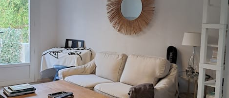 A living room with a sofa, a coffee table, a mirror, and a bookshelf.