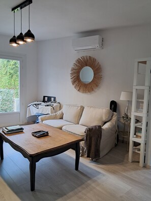 Ein Wohnzimmer mit einer Couch, einem Couchtisch, einem Spiegel und einem Bücherregal.