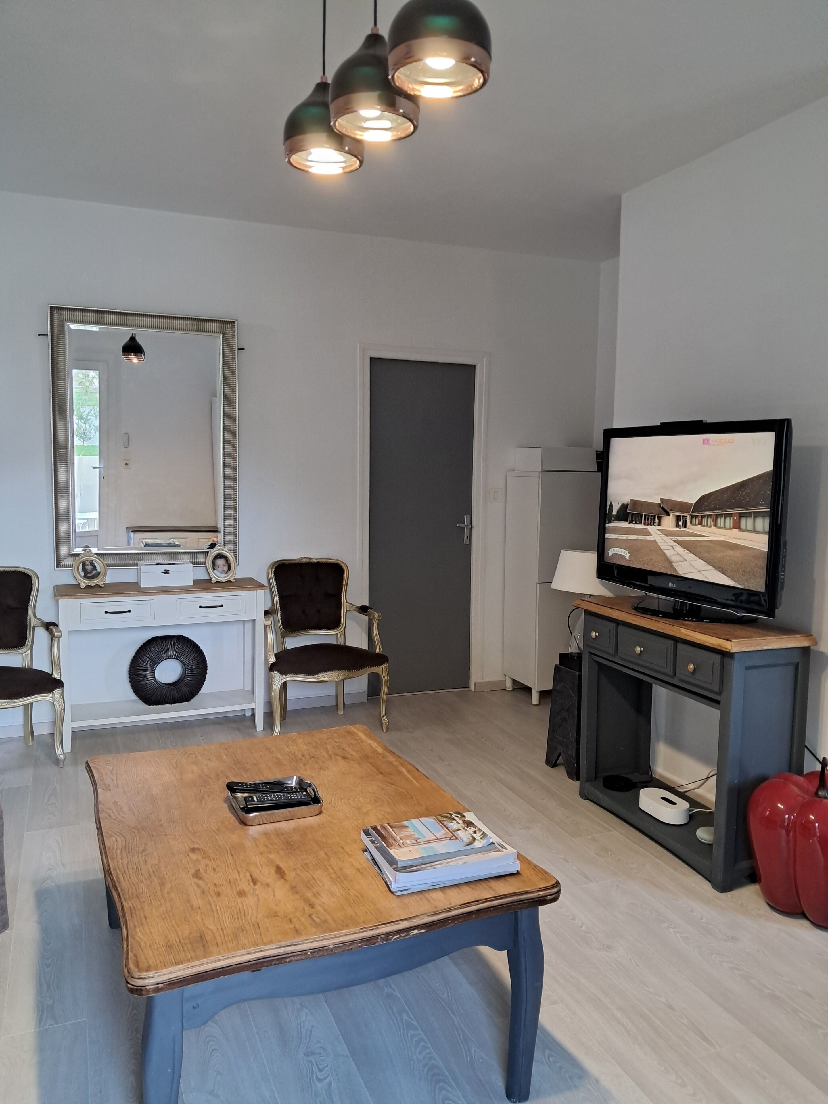 Ein modernes Wohnzimmer mit einem Holztisch, einem Fernseher und einem großen Spiegel.
