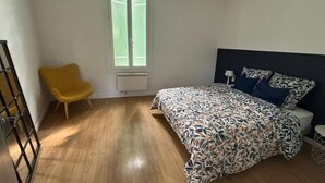 Une chambre à coucher avec un lit, une chaise, une fenêtre et un radiateur.