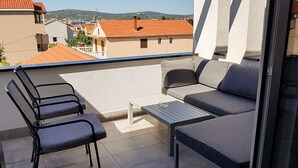 Un balcón con un sofá, dos sillones y una mesita.