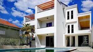 A modern two-story building with a swimming pool, a covered patio, and a staircase leading to the upper floor. - Nice apartment in Biograd na Moru (Biograd na Moru)
