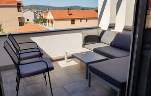Un balcon avec un canapé, deux fauteuils et une petite table.