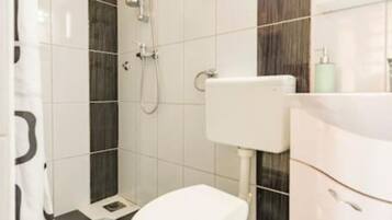 A bathroom with a toilet, a shower, and a sink.