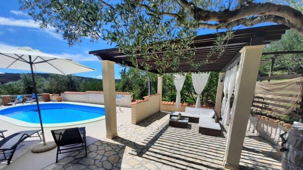 Et poolområde med pergola, liggestole og en fliseterrasse.
