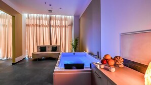Une salle de spa moderne avec une grande baignoire, un canapé incurvé et une présentation de fruits.