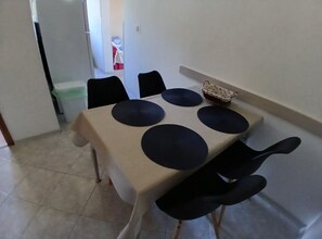 Une table à manger recouverte d’une nappe beige, entourée de six chaises noires.