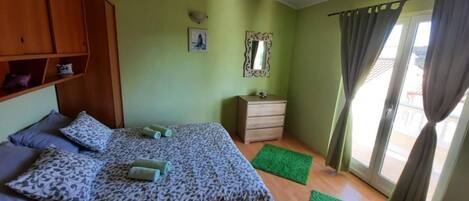 Un dormitorio con cama, cómoda, espejo y ventana con cortinas.