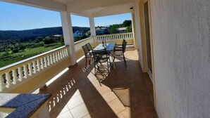 A covered balcony with a table and chairs, offering a view of the countryside. - Two Bedroom Apartment With Terrace (A3) (Kampor)