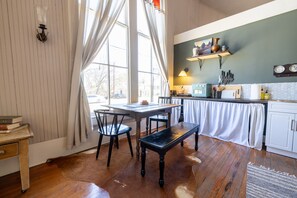 Uma cozinha acolhedora com piso de madeira, uma mesa de jantar, cadeiras e um banco.