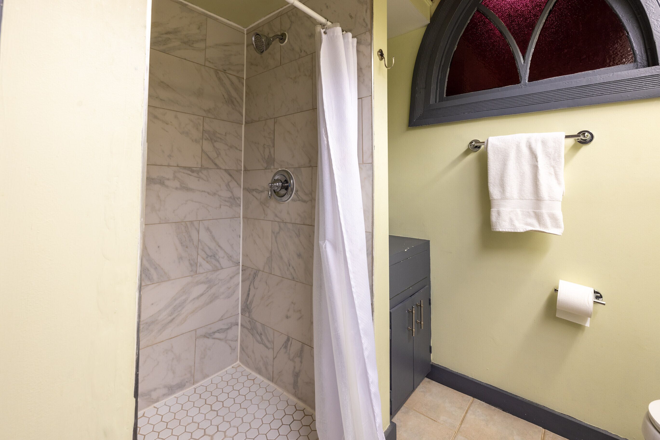 Un baño con ducha, inodoro y perchero para toallas.