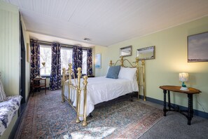 Een slaapkamer met een bed, nachtkastje, lamp en raam met gordijnen.
