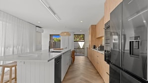 Una cocina moderna con un refrigerador de acero inoxidable, armarios de madera y una encimera blanca.