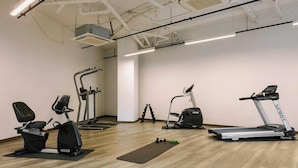 A gym with various exercise equipment including treadmills, stationary bikes, and elliptical machines. - Studio Queen Apartment (Detroit)