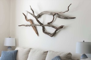 Een wandsculptuur van een tak in een woonkamer met een bank en twee lampen.