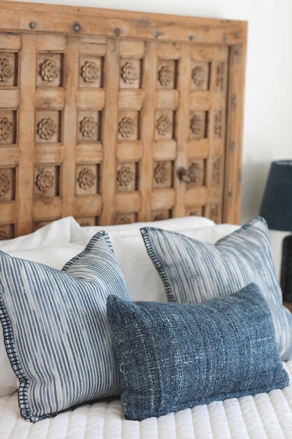 Een bed met een houten hoofdbord met bloemdecoraties, met twee kussens met strepen.