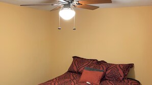 Un dormitorio con cama, ventilador de techo e iluminación.