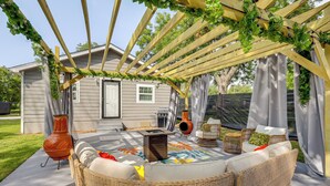 Un patio coperto con un divano in rattan, un vaso decorativo e un tavolino.