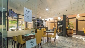 Ein Restaurant mit einem Buffetbereich, einer Bar und einer Sitzecke mit gelben Stühlen.