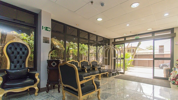 Eine Lobby mit Marmorboden, schwarz-goldenen Polstersesseln und einem großen Fenster mit Blick nach draußen.