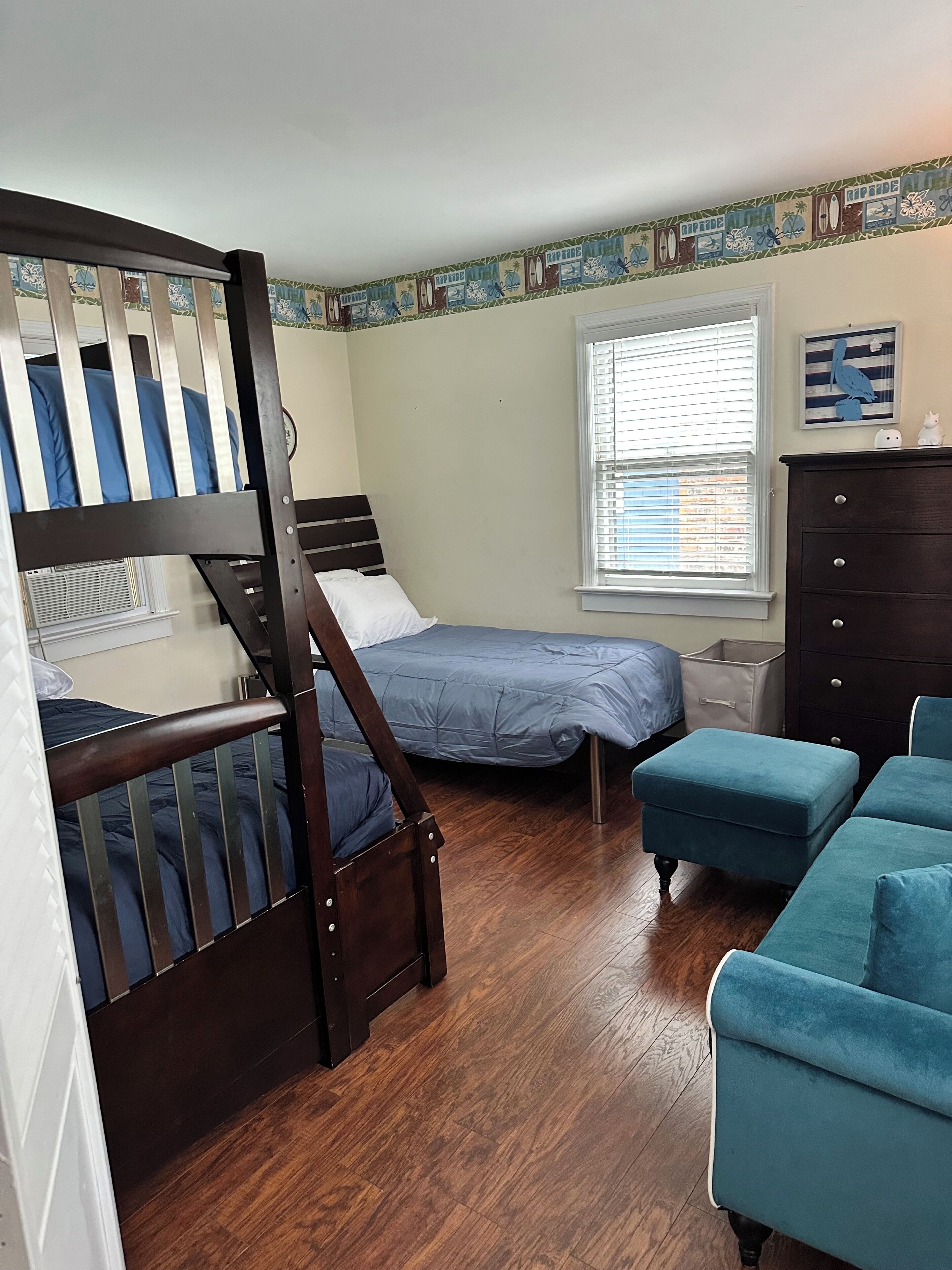 A bedroom with a bunk bed, a single bed, a dresser, and a window with blinds.