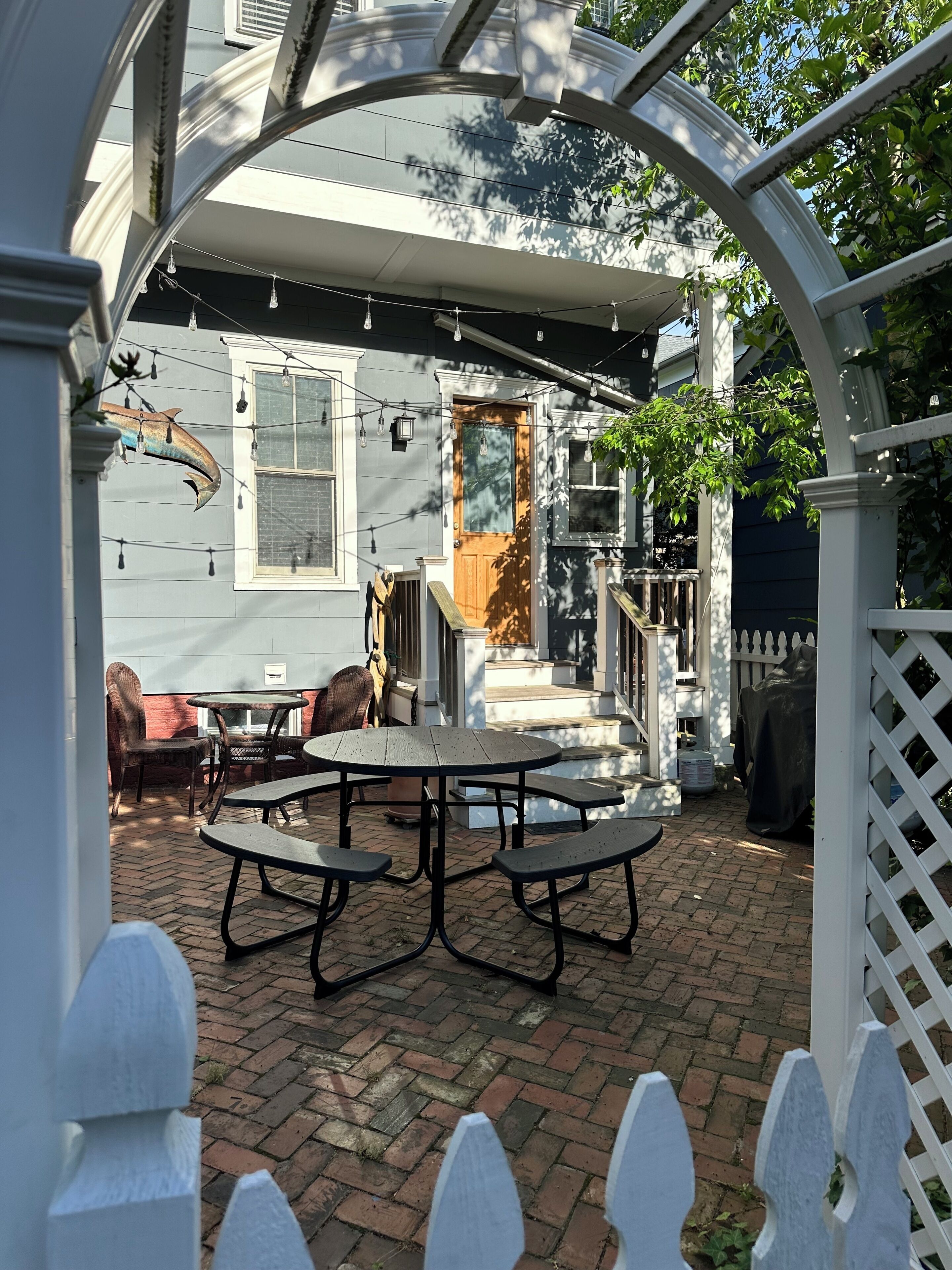 A patio with picnic tables, a wooden door, and a white picket fence.