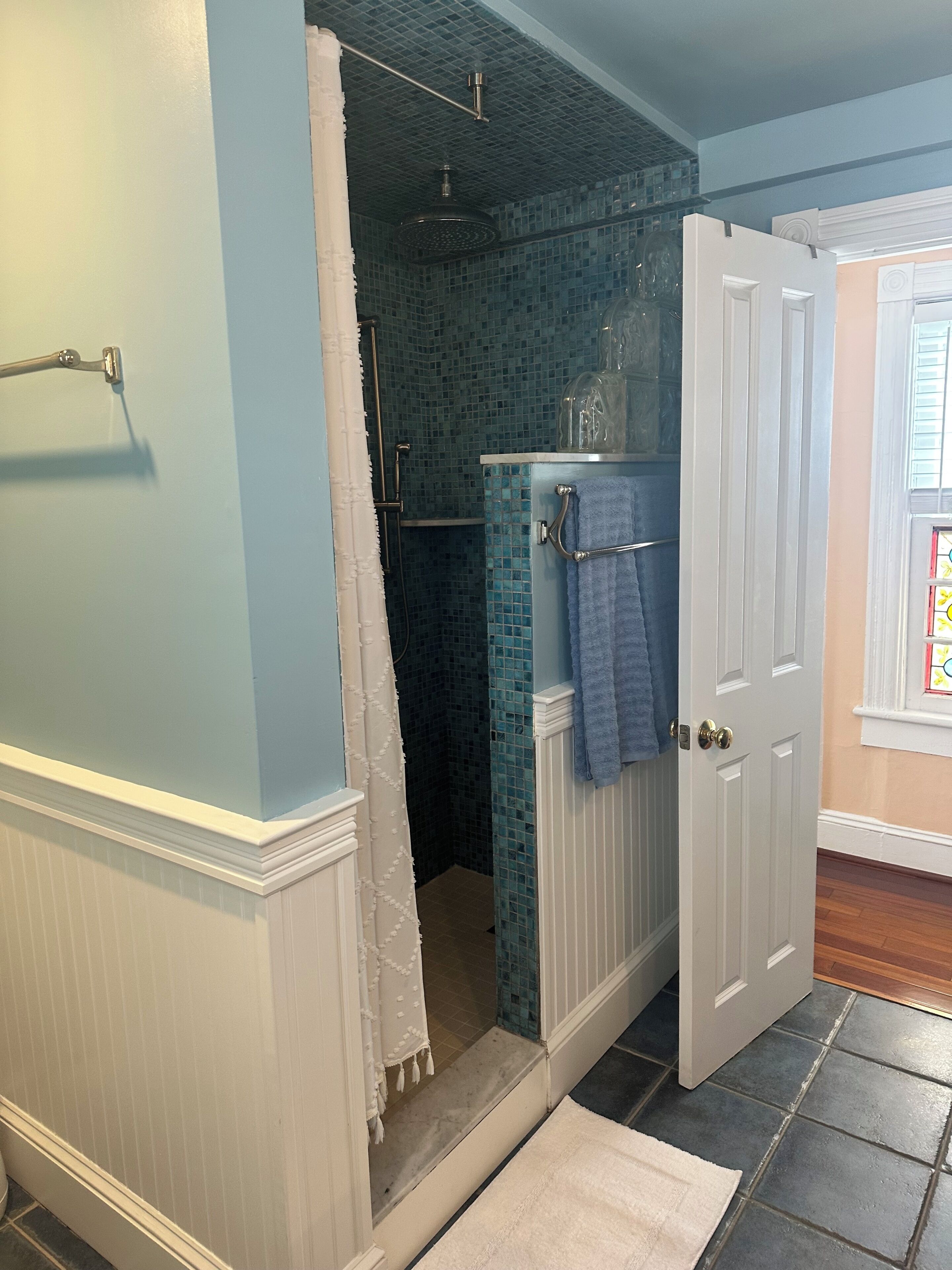 Une salle de bain avec une douche, un porte-serviettes et une porte.